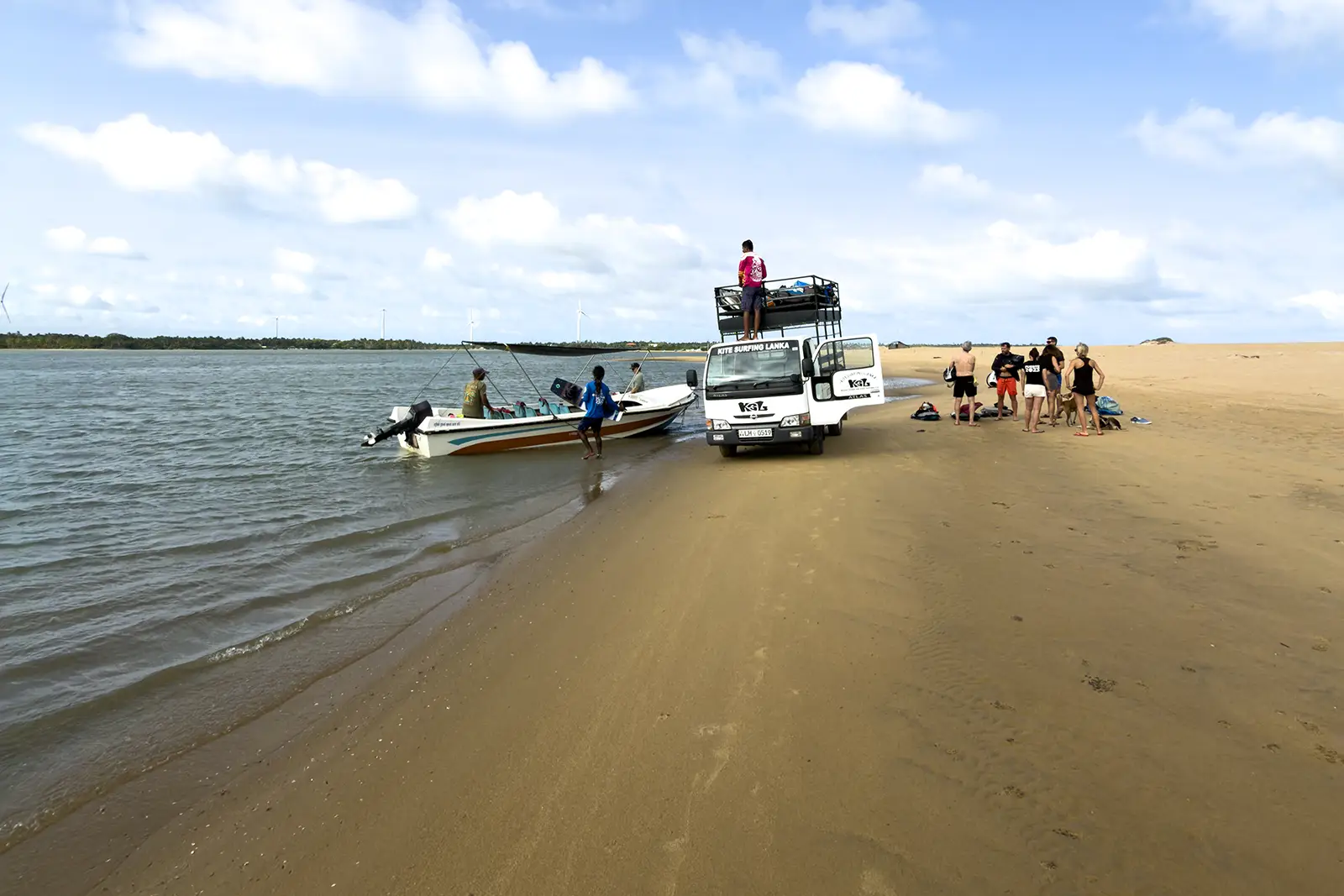 Kitesurfer in partenza verso lo spot di Vella Island a Kalpitiya in Sri Lanka con barca e mezzo di supporto sulla spiaggia