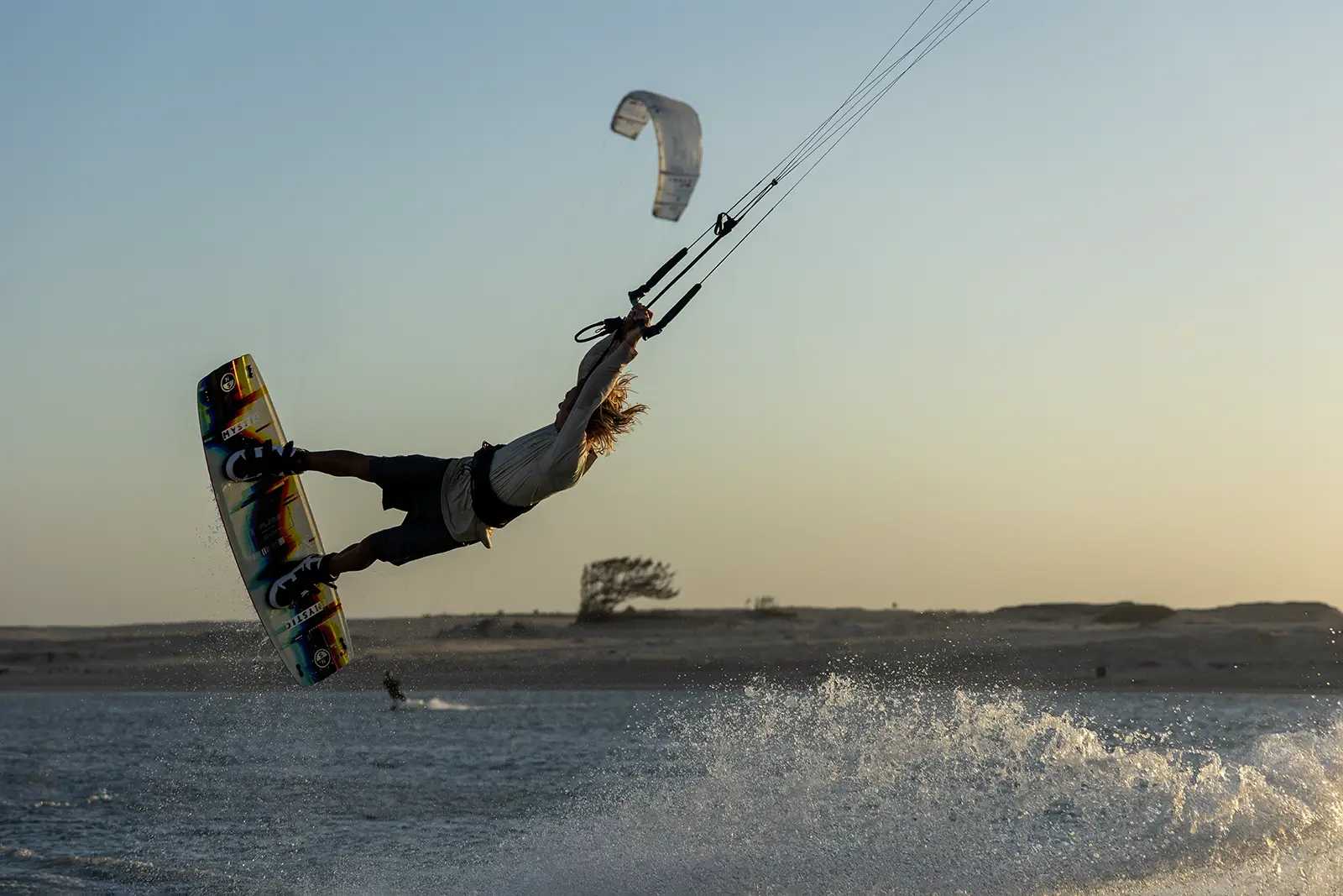 Kiter freestyle in fase di stacco sganciato sulla laguna di Ilha do Guajiru al tramonto, acqua increspata dal chop, Mondiale Freestyle GKA 2026