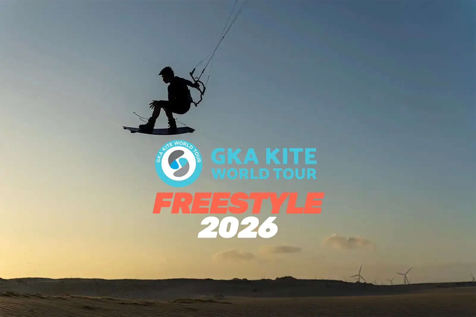 Kiter in silhouette durante un salto freestyle al tramonto sopra le dune, con il logo GKA Kite World Tour Freestyle 2026